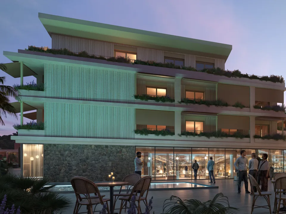 Un bâtiment de la résidence au crépuscule, ses terrasses plantées et ses commerces en rez-de-chaussée